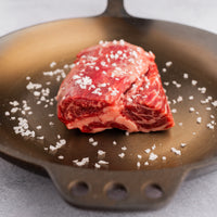 cap of ribeye with salt in skillet