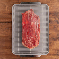 raw flank steak on rack in pan 