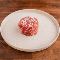 highly marbled raw filet mignon with salt on white plate 