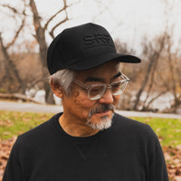 Man wearing a black cap with 'SRF' logo outdoors