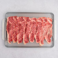 Raw Wagyu NY strip slices on rack in pan 