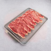 raw NY strip slices on rack and pan 