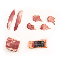 Raw kurobuta pork pieces and a package of bacon on a white background