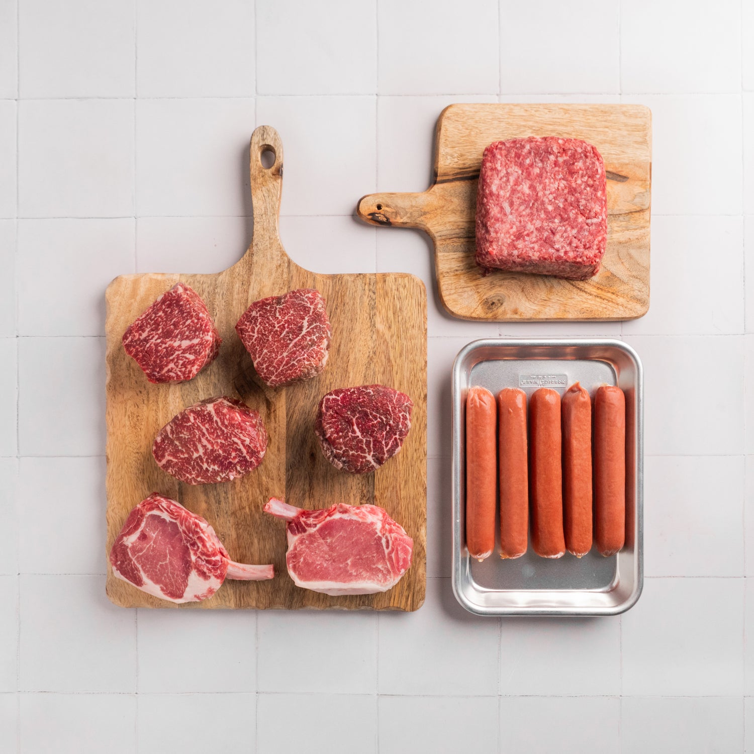 Assortment of fresh meats including two Kurobuta Frenched Pork Chops, American Wagyu Ground Beef, a SRF Black® Filet Mignon, American Wagyu Hot Dogs, and two SRF Gold® Ribeye Filets.