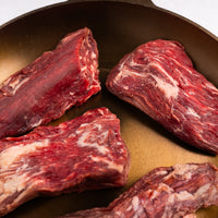 Raw beef chunks in a cast iron skillet