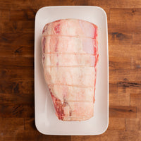 Raw eye of ribeye roast on a white plate on a wooden surface