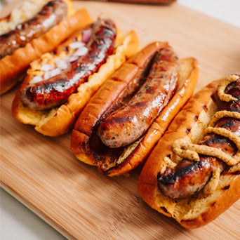 Three sausage dogs with various toppings on a wooden board