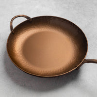Bronze frying pan on a light gray background