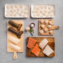 Assorted raw seafood on cutting boards and trays on a gray surface