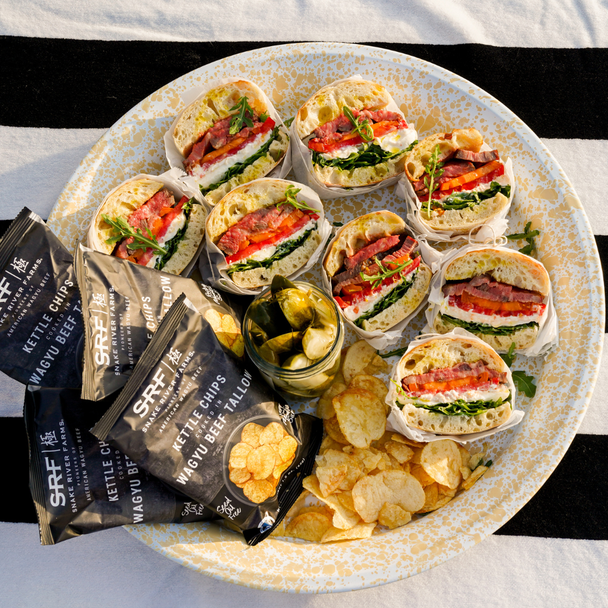 Summer Sandwiches and bags of SRF potato chips and jar of pickles on a plate with a black and white stripped clothe