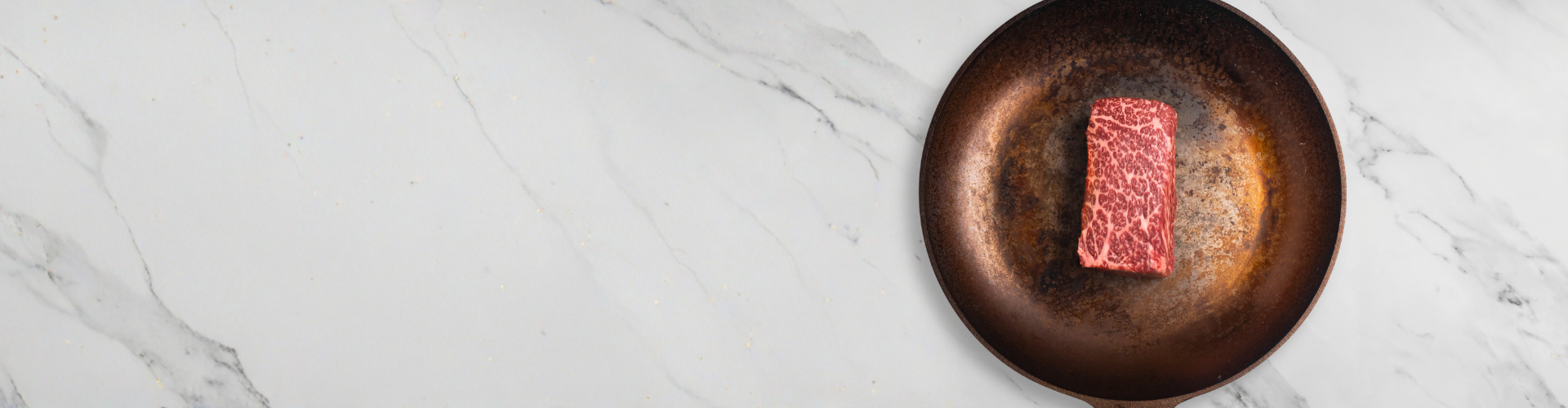 Raw steak on a copper pan with a marble background