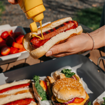 Hot dog being topped with mustard at a casual outdoor setting