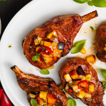Grilled lamb chops with a colorful salsa on a white plate