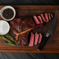 cooked and sliced dry-aged Porterhouse steak on cutting board 