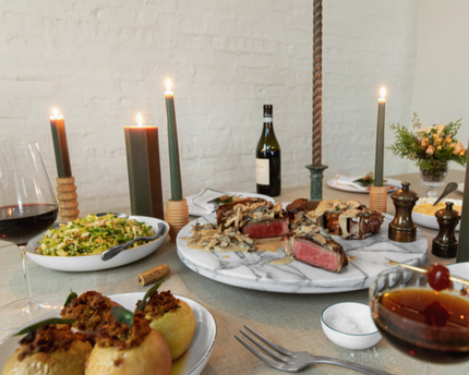 Steak dinner on a holiday table with sides and candles and drinks