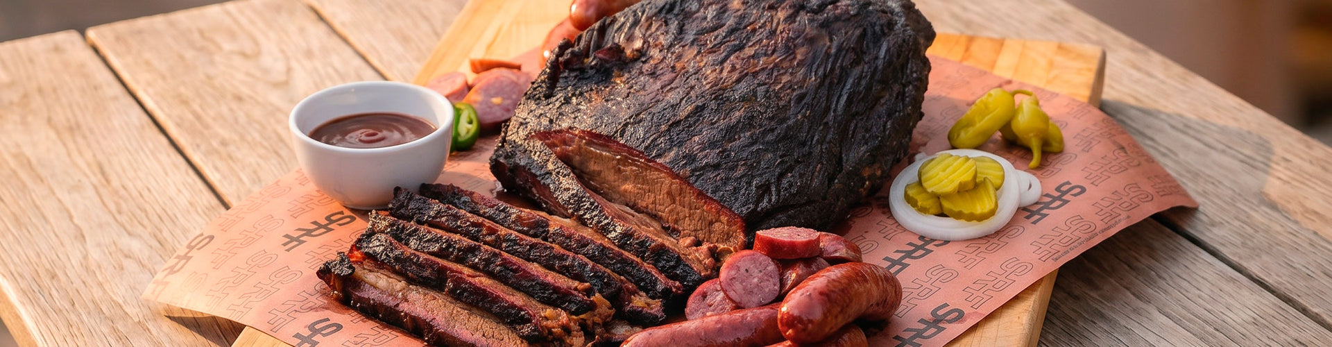 Smoked Brisket platter with pickles and sauce on a wooden table