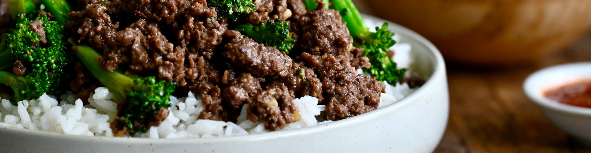 Bowl of beef and broccoli with rice on a wooden table