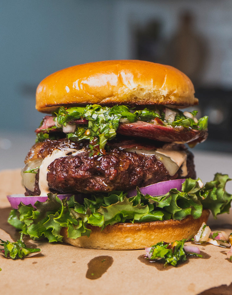 Delicious-looking burger with lettuce, tomato, and other ingredients on a bun.