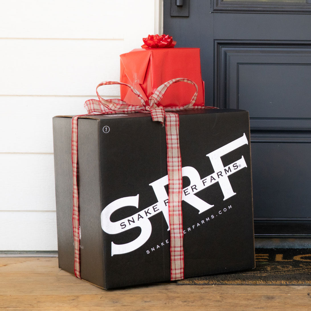 Gift box with 'Snake River Farms' branding and a red bow in front of a door.
