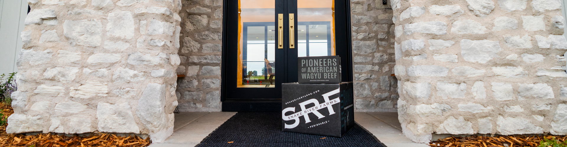 Black door with gold handle and 'Pioneers of American Wagyu Beef' branding in a stone building entrance.