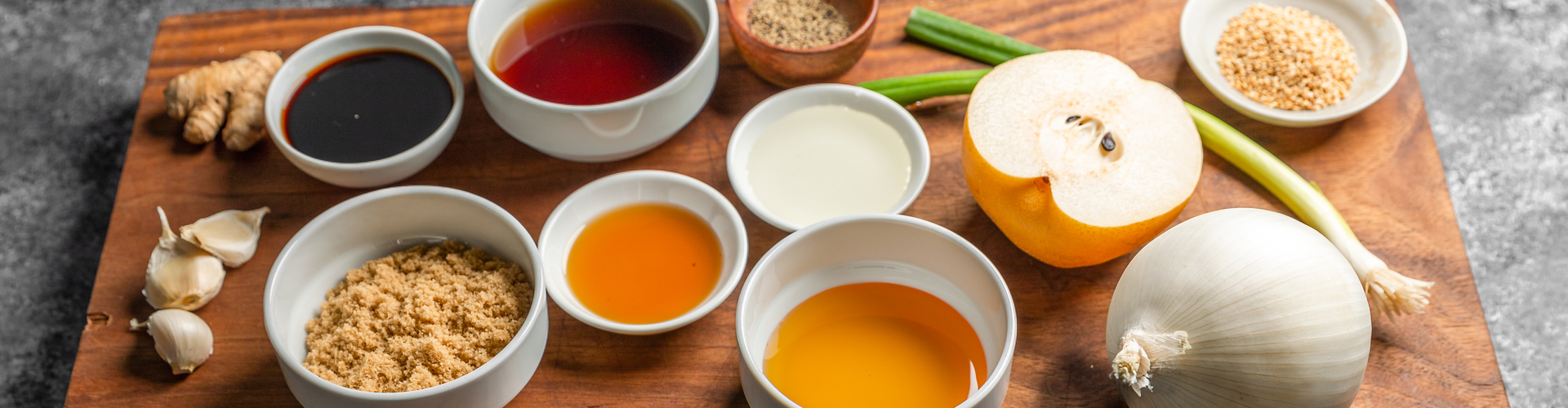 Assorted ingredients including a lemon, onion, and various seasonings on a wooden board.