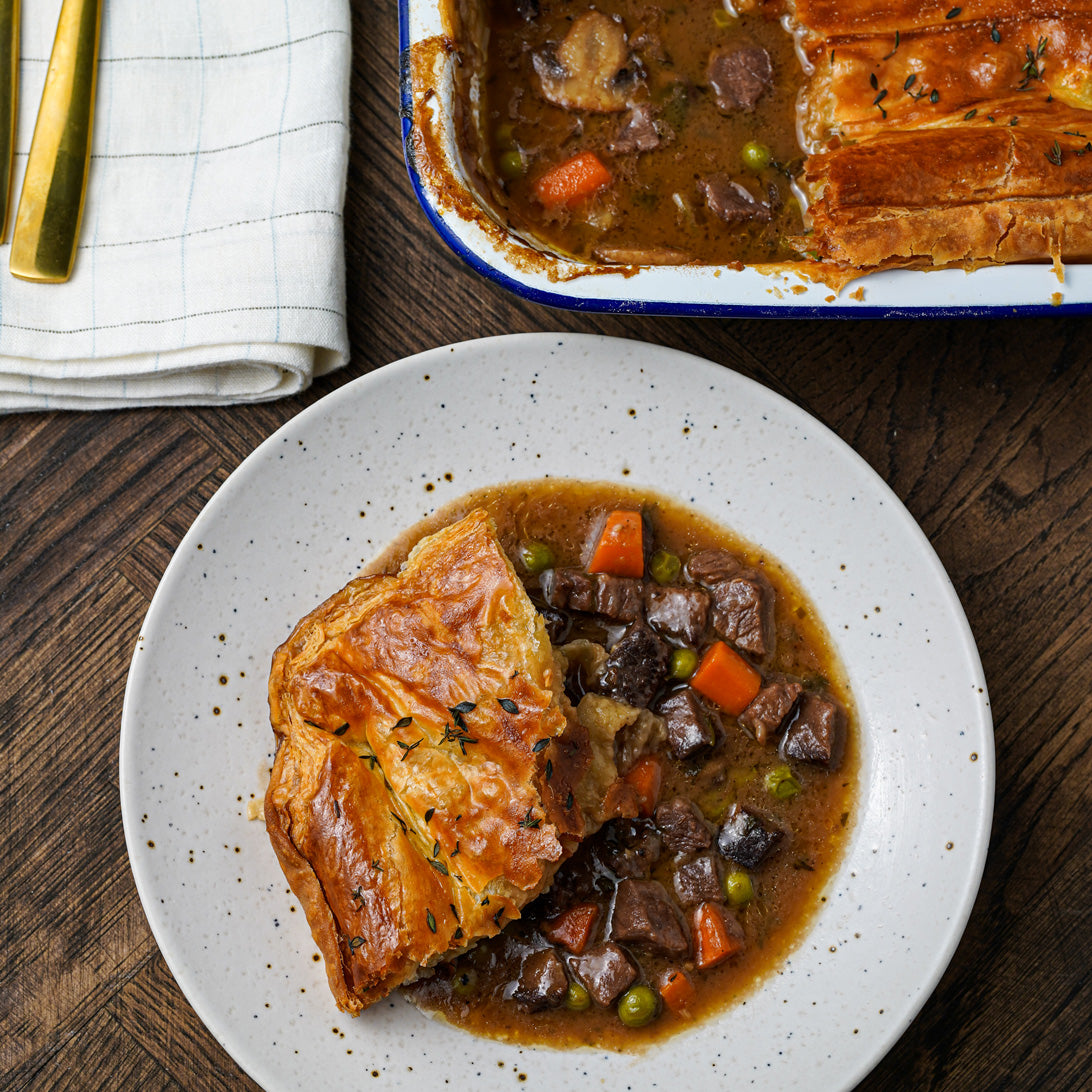 Pot Pie with a serving on a plate and the rest in a dish on a wooden table.