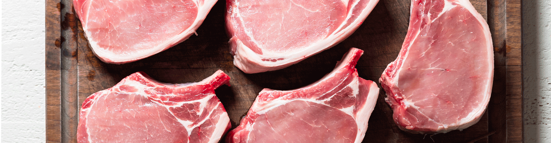 Close up of raw pork chops on a cutting board 