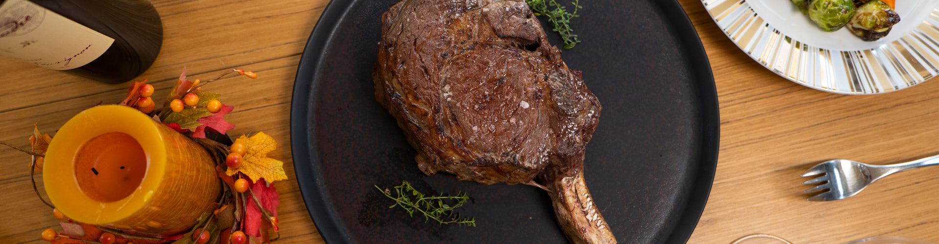 Ribeye Steak on a black plate with a candle and wine bottle in the background