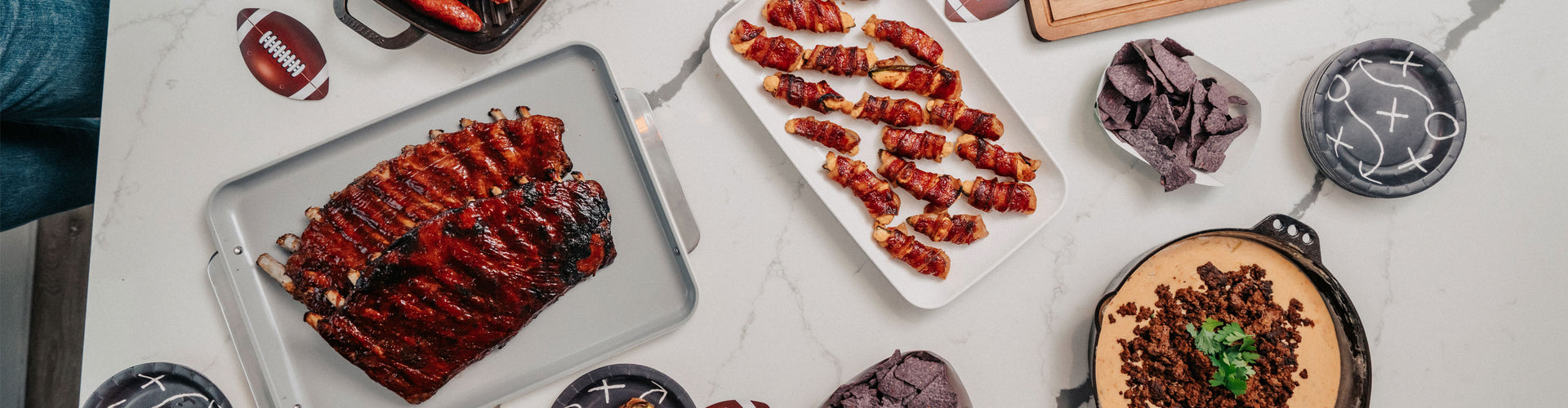 Assorted food items including roasted meats, dips, and sides on a white surface.