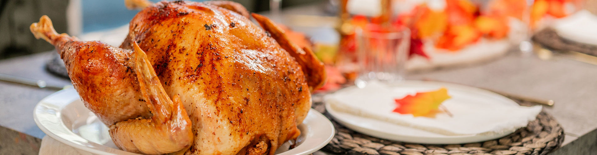 Roasted turkey on a plate with a blurred background of a festive table setting.
